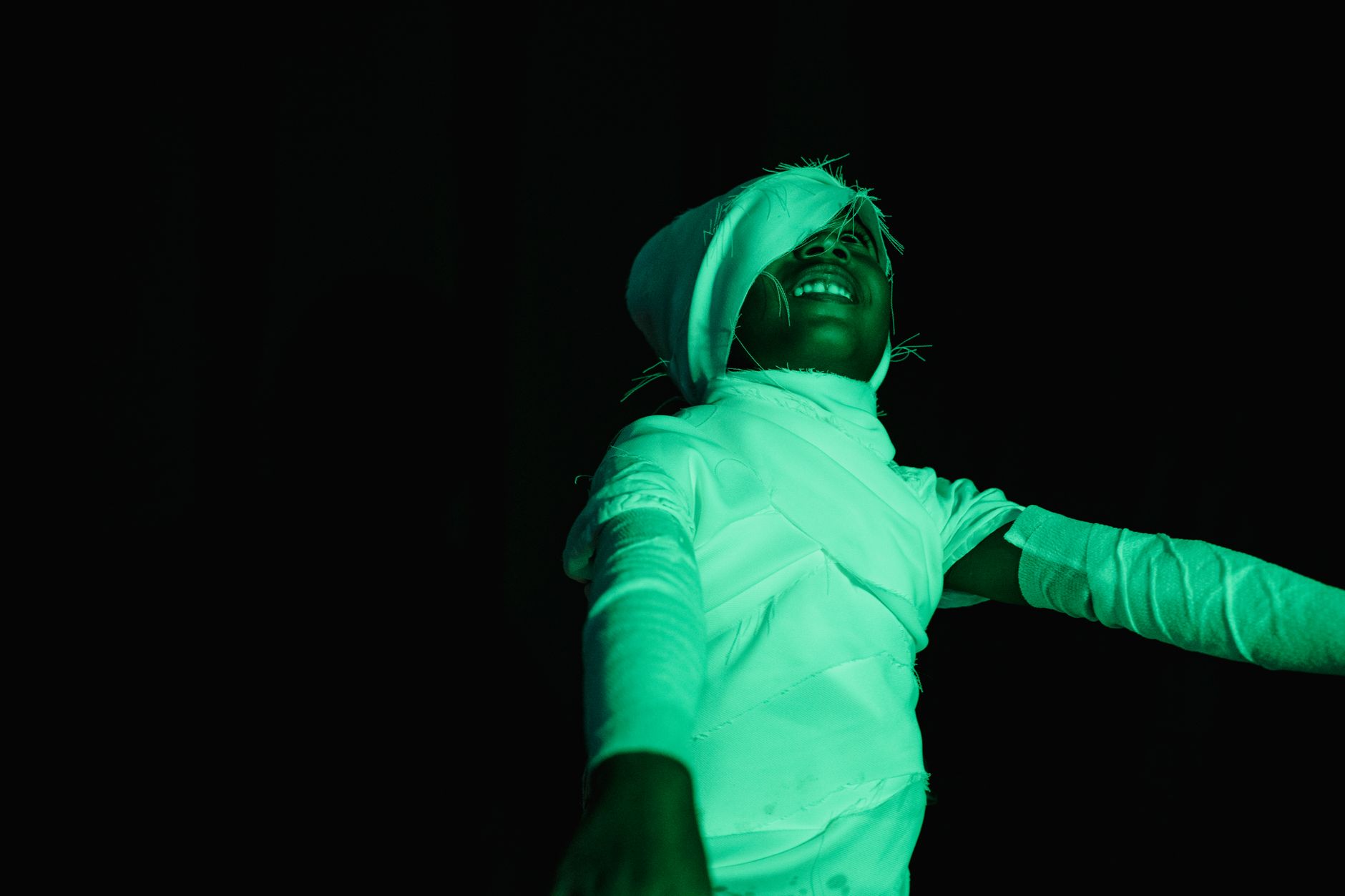 glow in the dark party cairo — Child in a mummy costume having fun with dramatic lighting on a dark background.
