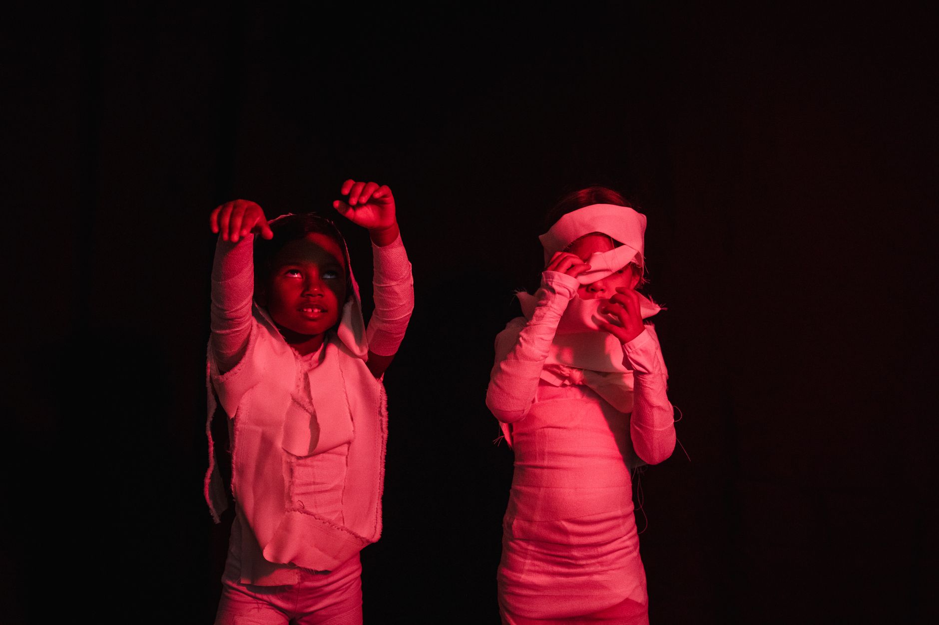 university fresher week entertainment Egypt — Two children dressed as mummies under red lighting for Halloween.