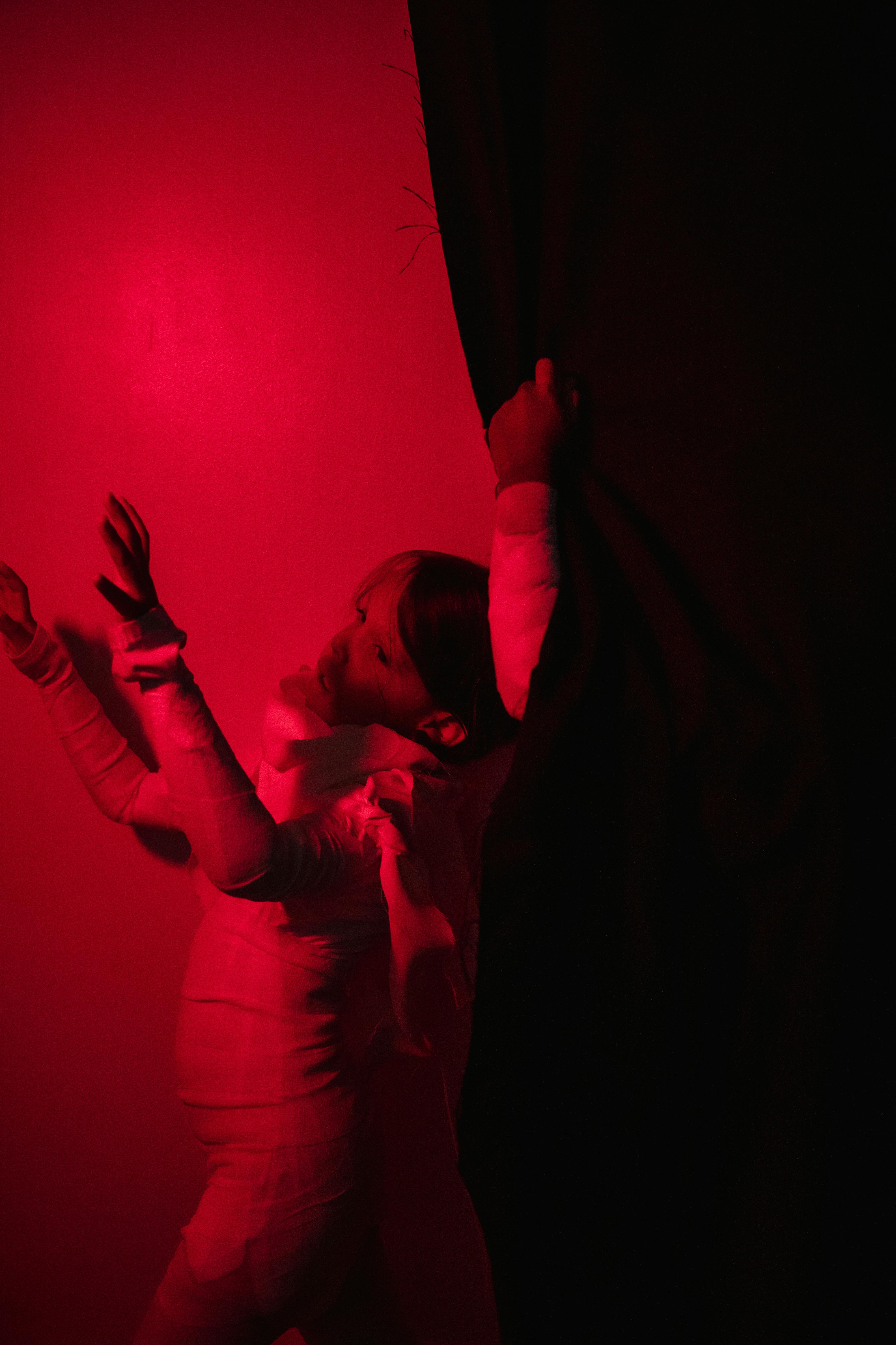 Free A child in a mummy costume poses dramatically with red lighting, ideal for Halloween themes. Stock Photo