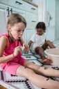 Girls sitting on floor in bathroom sticking Halloween tatoo