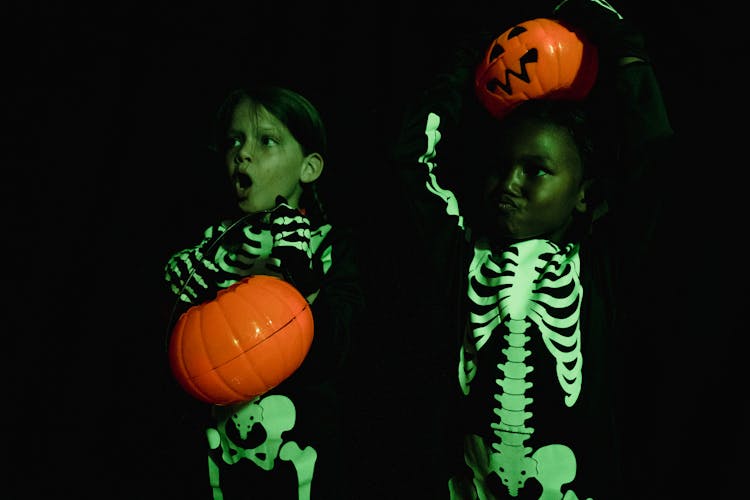 Two Kids Wearing Skeleton Costumes Holding Pumpkin Heads