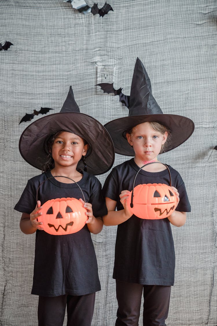 Two Girls disguised As Wizards With Pumpkin Heads In Hands