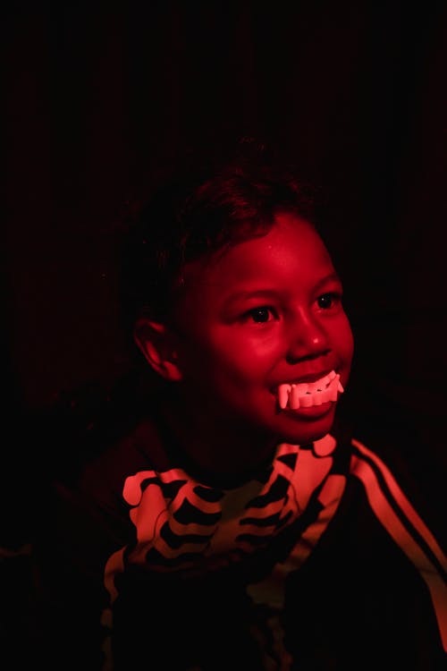 Black child with toy teeth and wearing skeleton costume