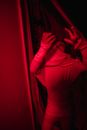 Kid standing in red-lit room with raised arms in spooky posture