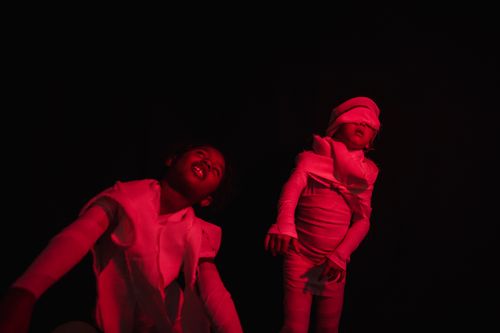 Free Two children wrapped in bandages and bathed in red light, pretending to be mummies in a studio setting. Stock Photo