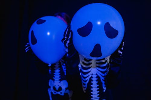 Characters wearing skeleton costumes with spooky balloons imitating heads