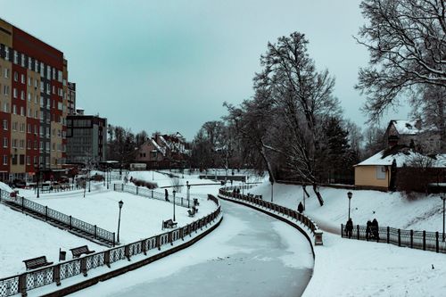 Free Charming winter landscape with snow-covered river and buildings, perfect for winter travel themes. Stock Photo