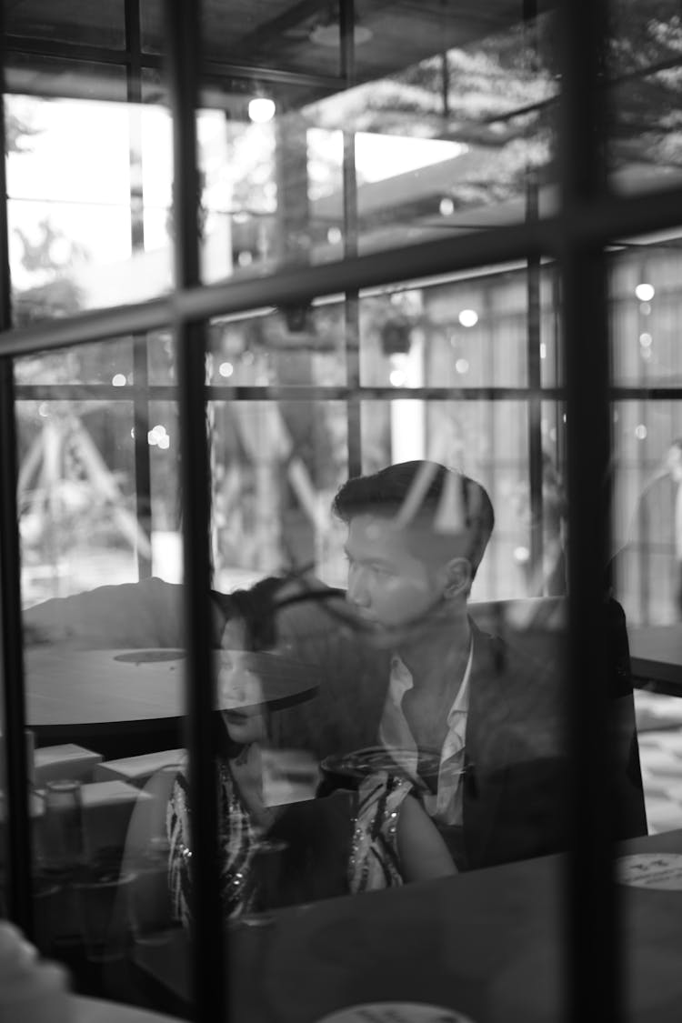 Black And White Photo Of A Couple In A Restaurant Seen Through The Window 