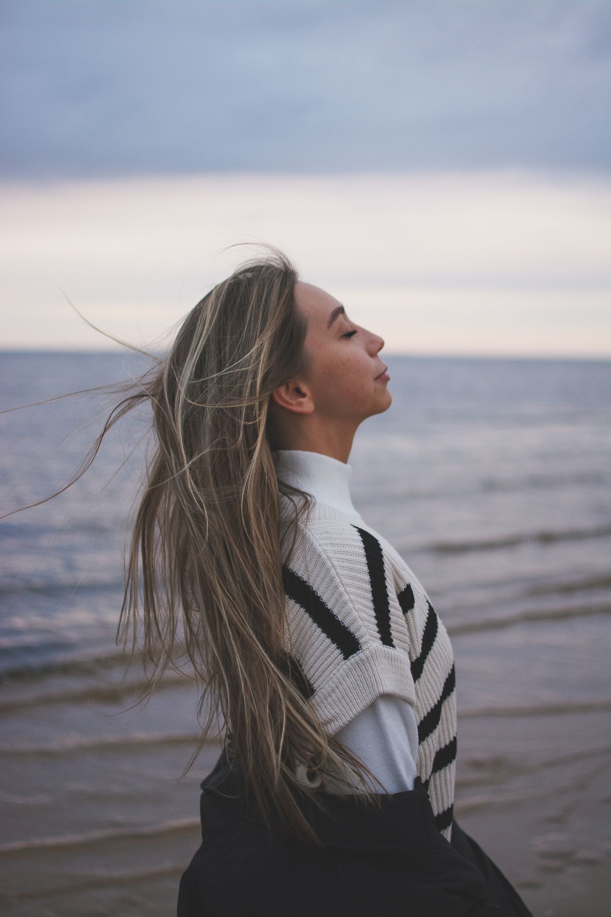 Woman breathing calmly by the sea at dusk