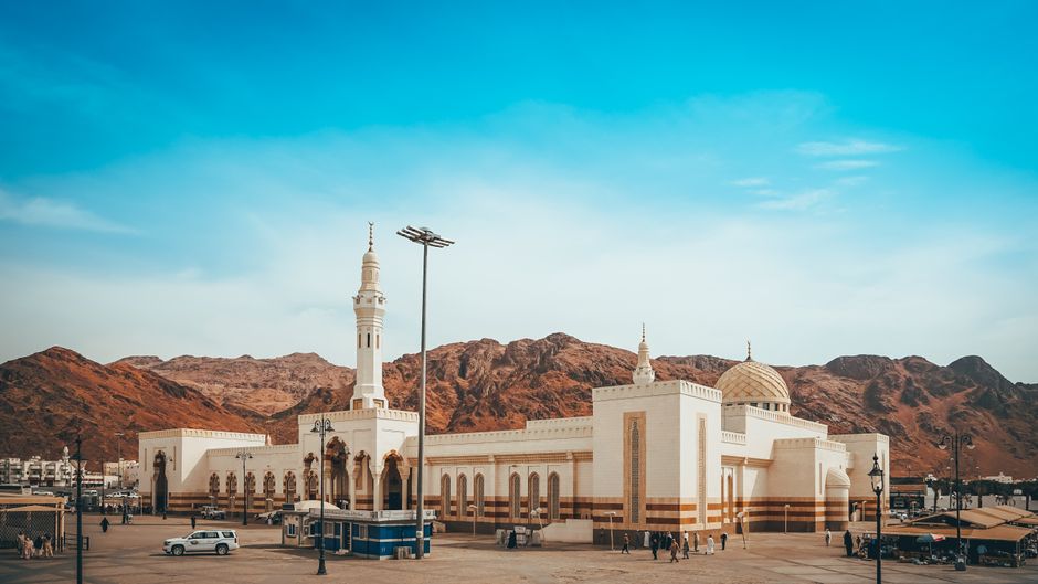 Captured in Medina, this image showcases a beautiful mosque against a backdrop of mountains and blue sky.