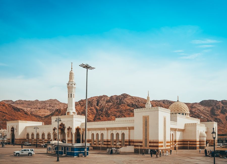 Captured in Medina, this image showcases a beautiful mosque against a backdrop of mountains and blue sky.