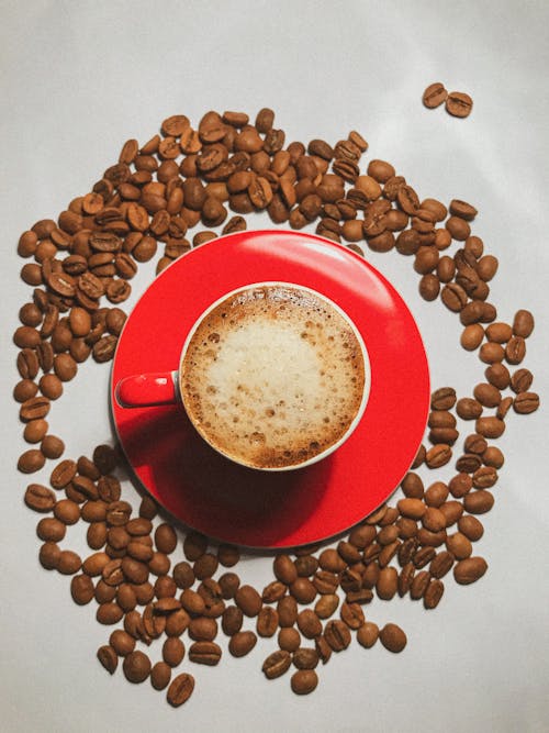 Close-Up Shot of a Cup of Coffee Surrounded by Coffee Beans