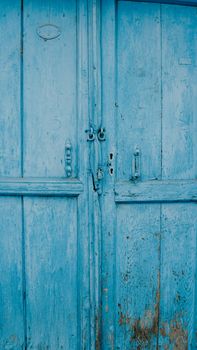A close-up view of a weathered blue wooden door, showcasing rustic vintage charm and natural texture.