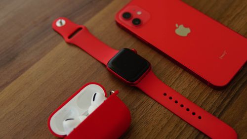 Free Close-up of red smartphone, smartwatch, and earbuds on wooden table. Stock Photo