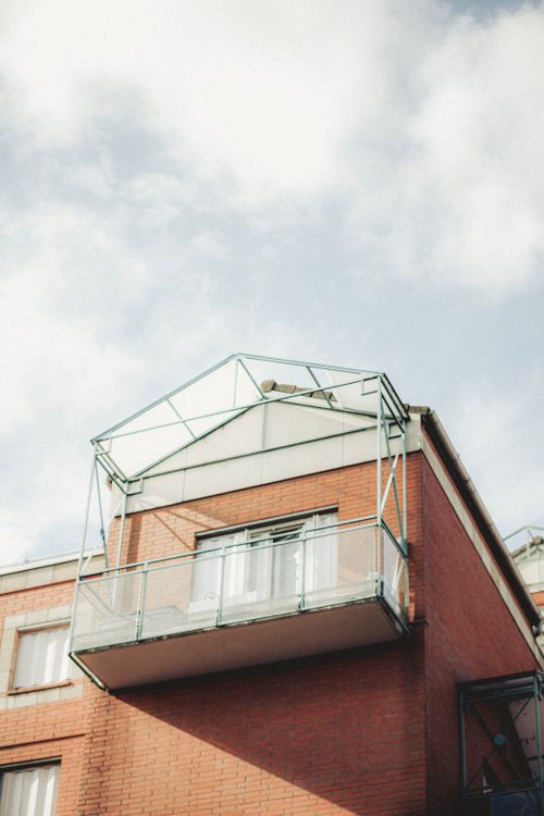 Free A stylish modern brick house featuring a glass balcony against a backdrop of a clear blue sky. Stock Photo