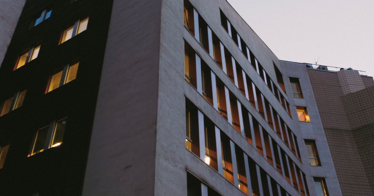 Modern hospital building with green cross signage at dusk
