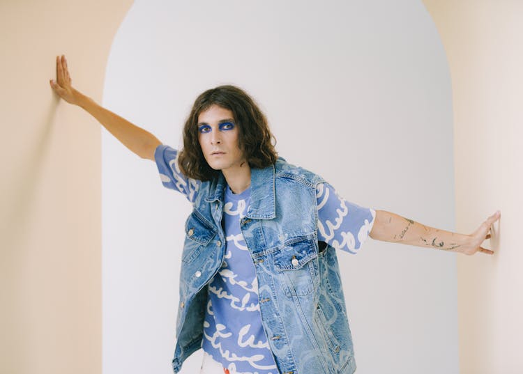 Transsexual Man With Long Hair And Makeup Standing Between Walls