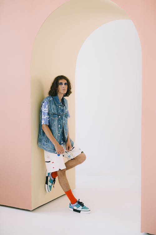 Transsexual man with makeup standing under arcade and resting against pillar