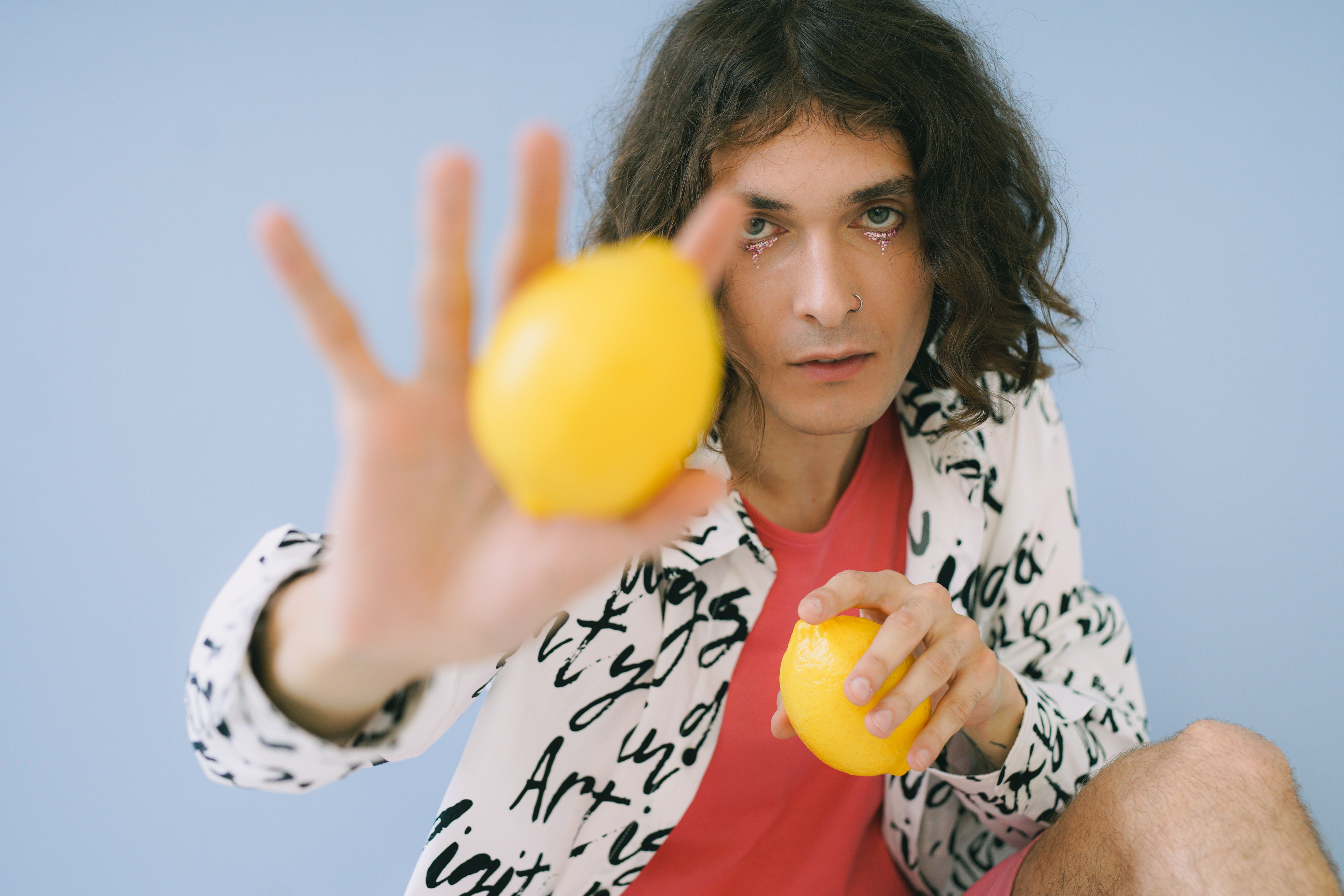 Artistic portrait of a man holding lemons on a blue backdrop.