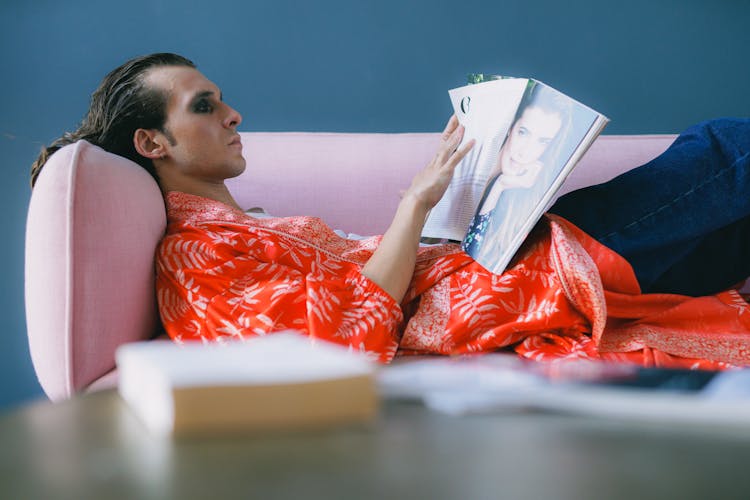 Man Reading Magazine On Pink Sofa