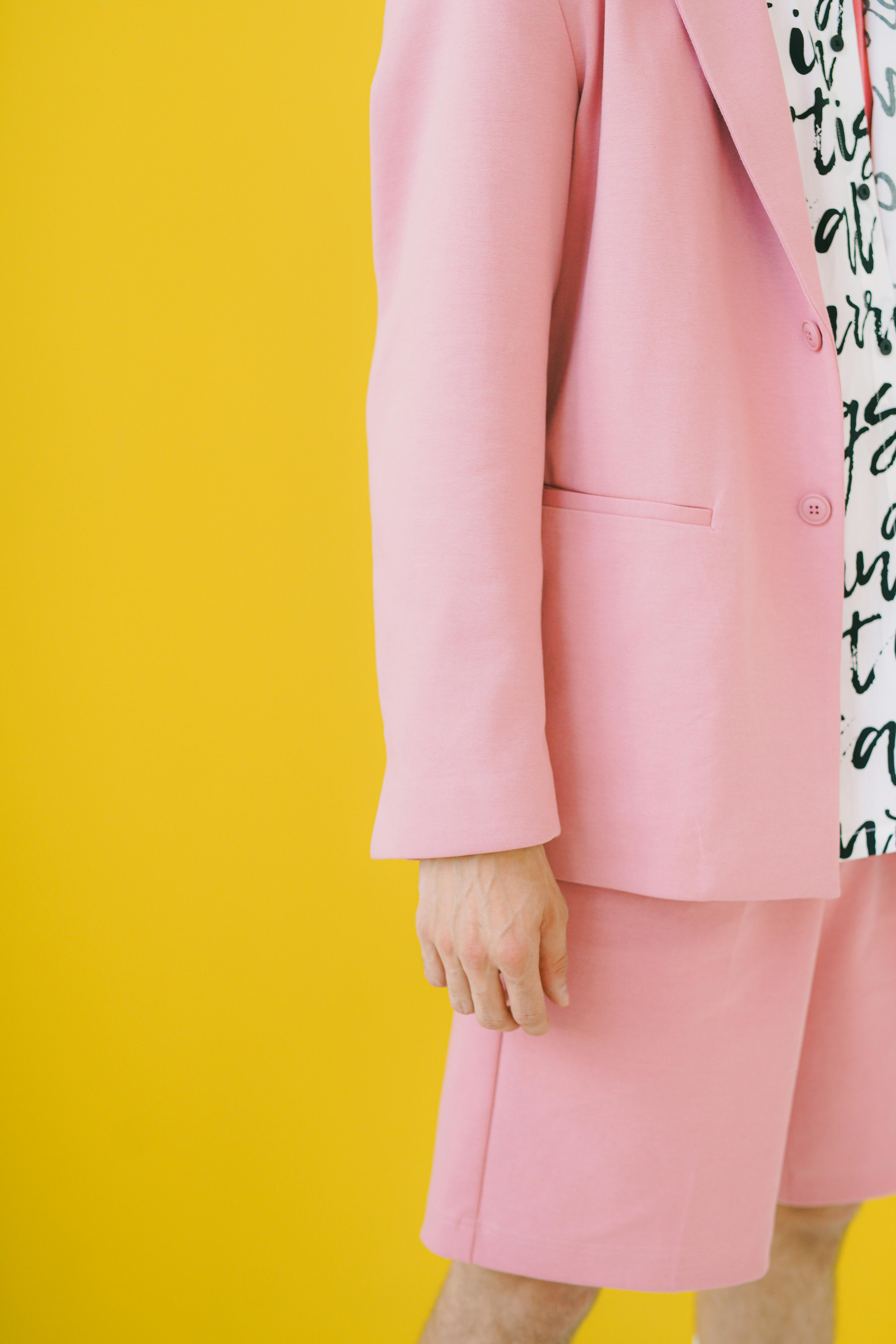 A fashionable pink suit with a printed shirt against a vibrant yellow backdrop.