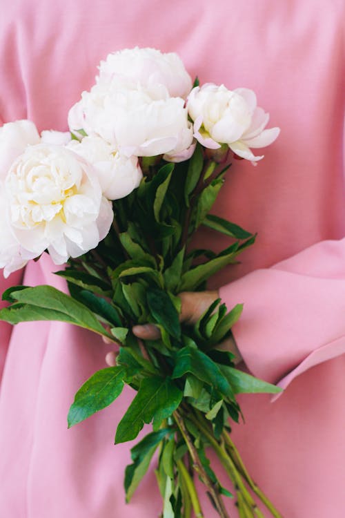 Holding flowers behind back 