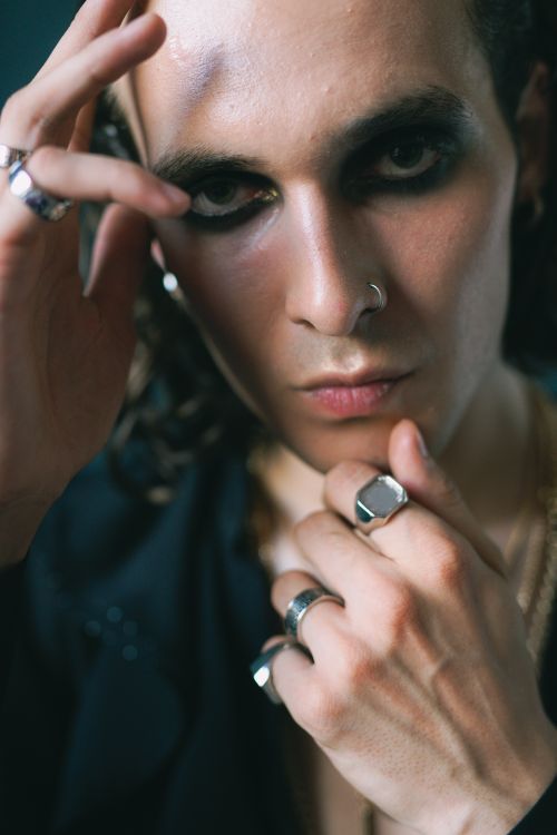 Free A charismatic man with makeup and jewelry looking intensely at the camera in a studio. Stock Photo