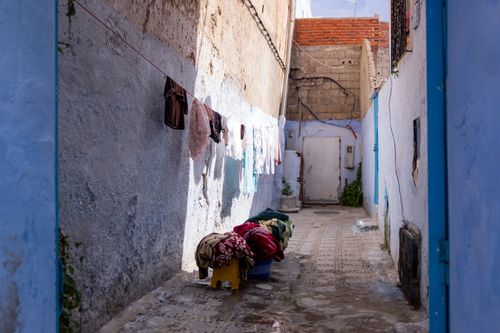 Free Sunlit alley with hanging clothes and shadows cast on weathered walls. Stock Photo
