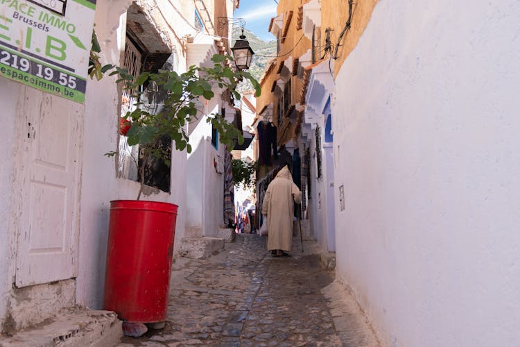 A Person In A Robe With A Hoodie Walking On An Alleyway