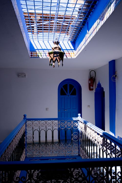 Free Charming indoor setting featuring a blue door, ornate railings, and a skylight. Stock Photo