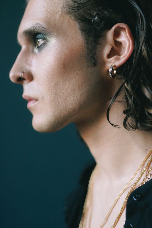 Free Close-up portrait of a young adult with earrings and makeup, showcasing modern fashion and style. Stock Photo