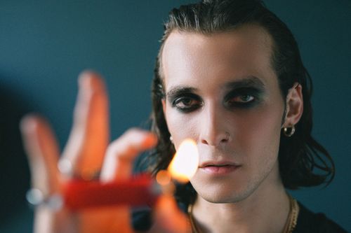 Free Close-up of a man holding a lighter with intense eye makeup, creating a dramatic portrait. Stock Photo