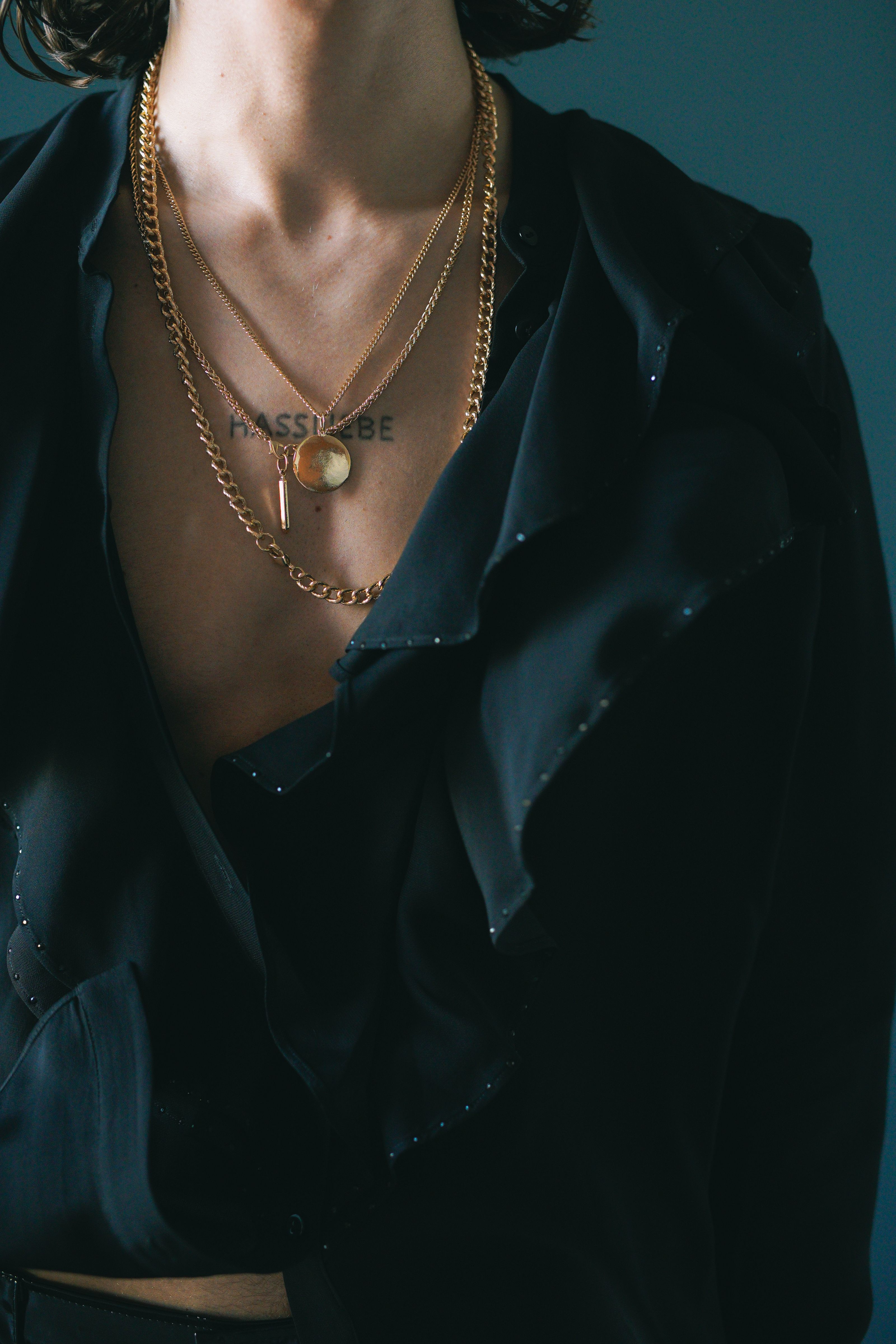 Foto de close-up estilosa de colares de ouro combinados com uma camiseta preta, destacando tendências modernas de moda.