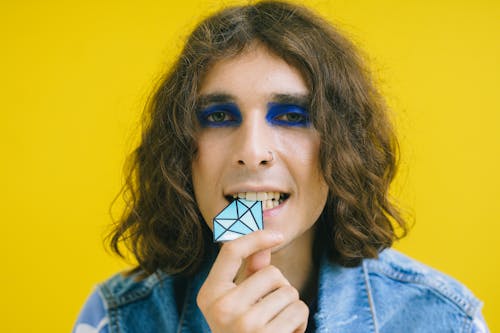 Man with Blue Eyeshadow Biting a Diamond