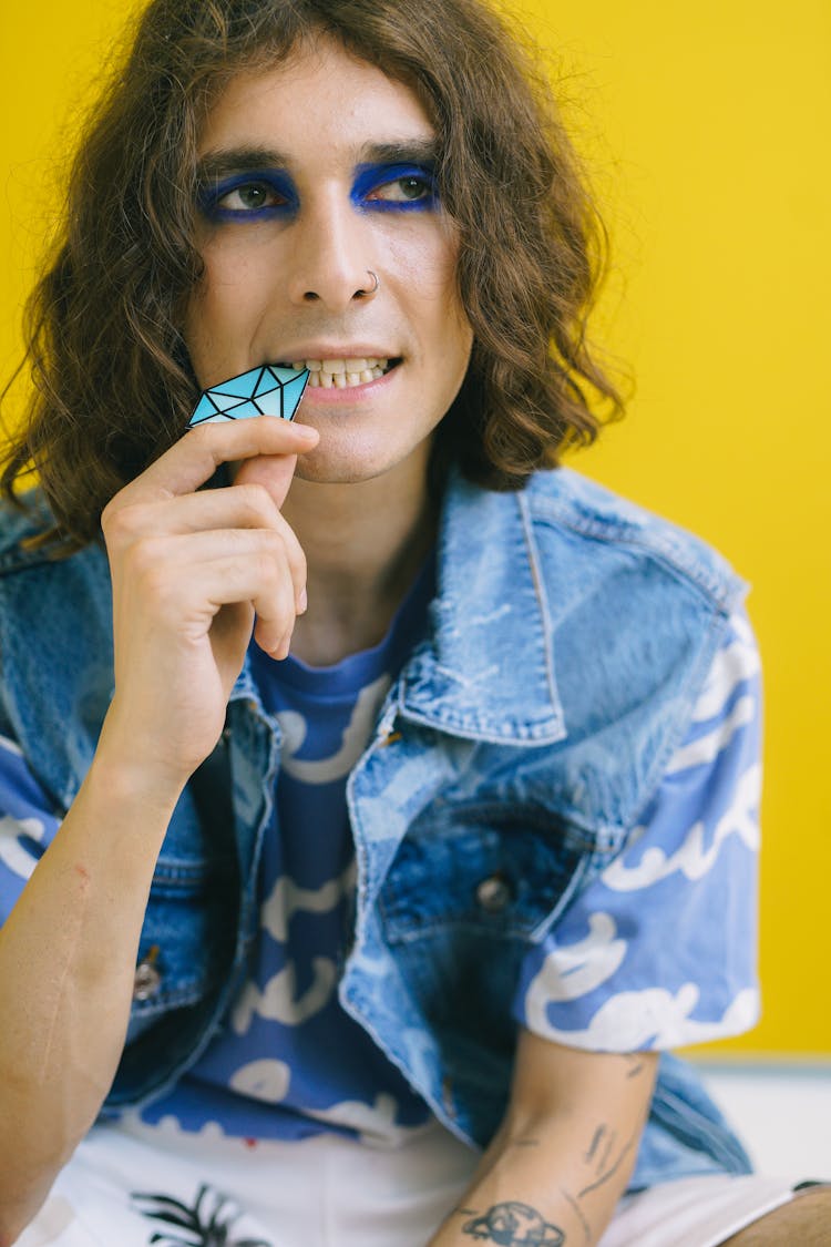 A Man In A Denim Jacket Biting A Diamond Paper Cutout