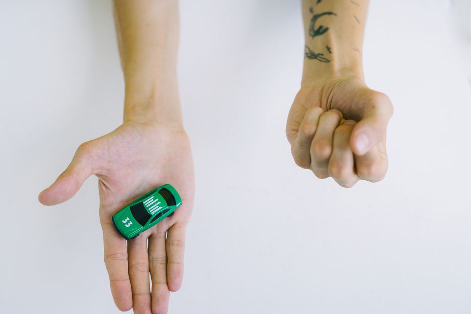 How to Lower Your Car Insurance Premium: 10 Proven Tips Close-up of hands holding a green toy car, symbolizing control and playfulness.