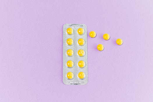 Close-up of yellow pills in blister pack on purple surface, emphasizing modern healthcare.