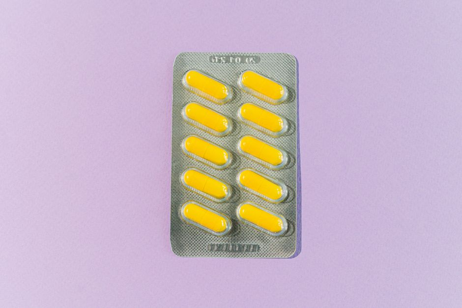 A blister pack of yellow pills on a purple background, symbolizing healthcare and medication.