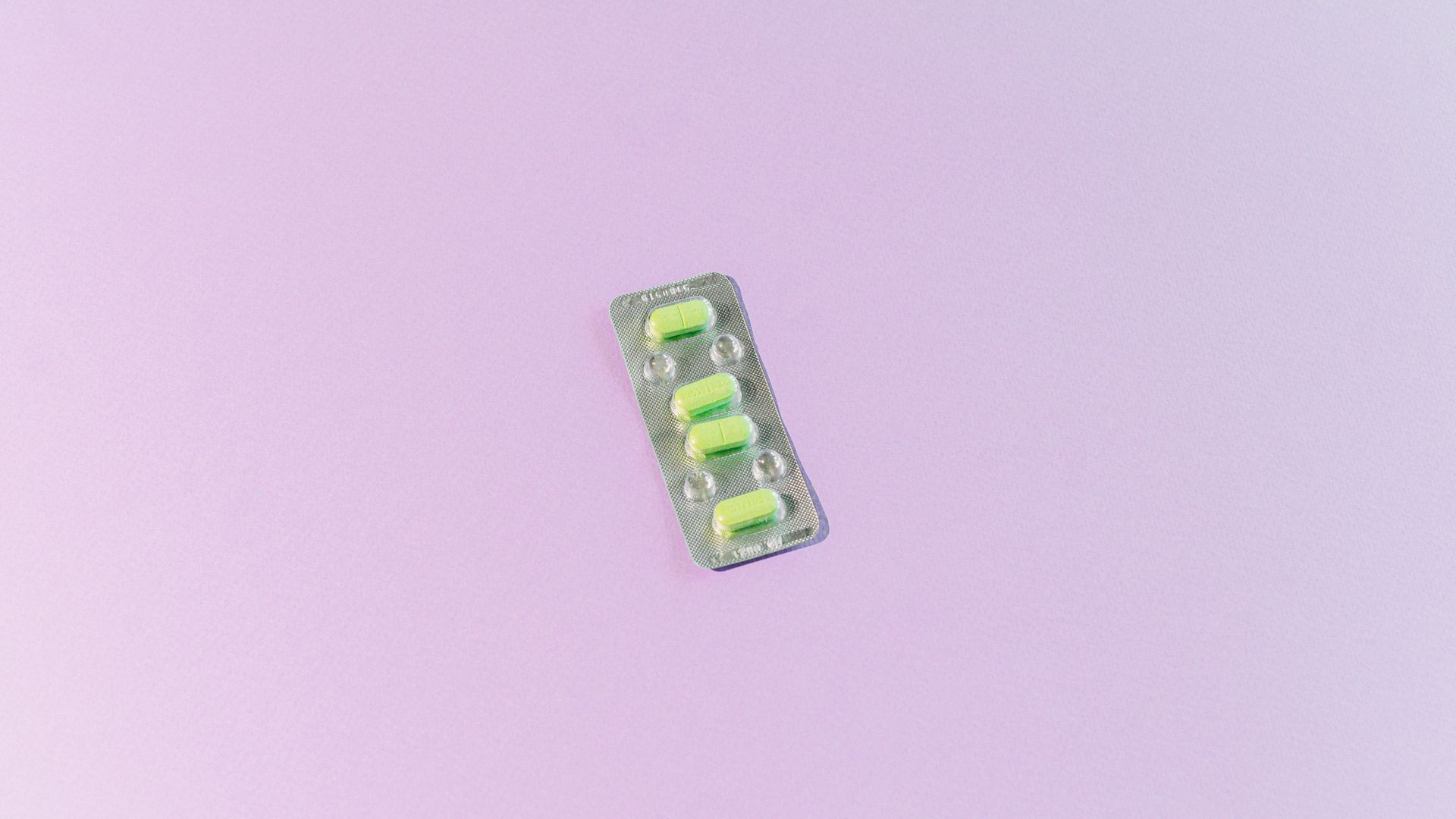 High angle view of blister pack with yellow pills on a light purple background, providing ample copy space — modalert 200mg review