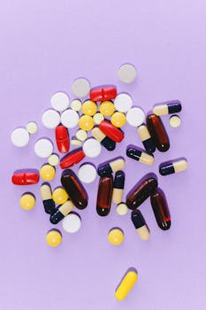 A collection of colorful capsules and tablets on a light purple surface.