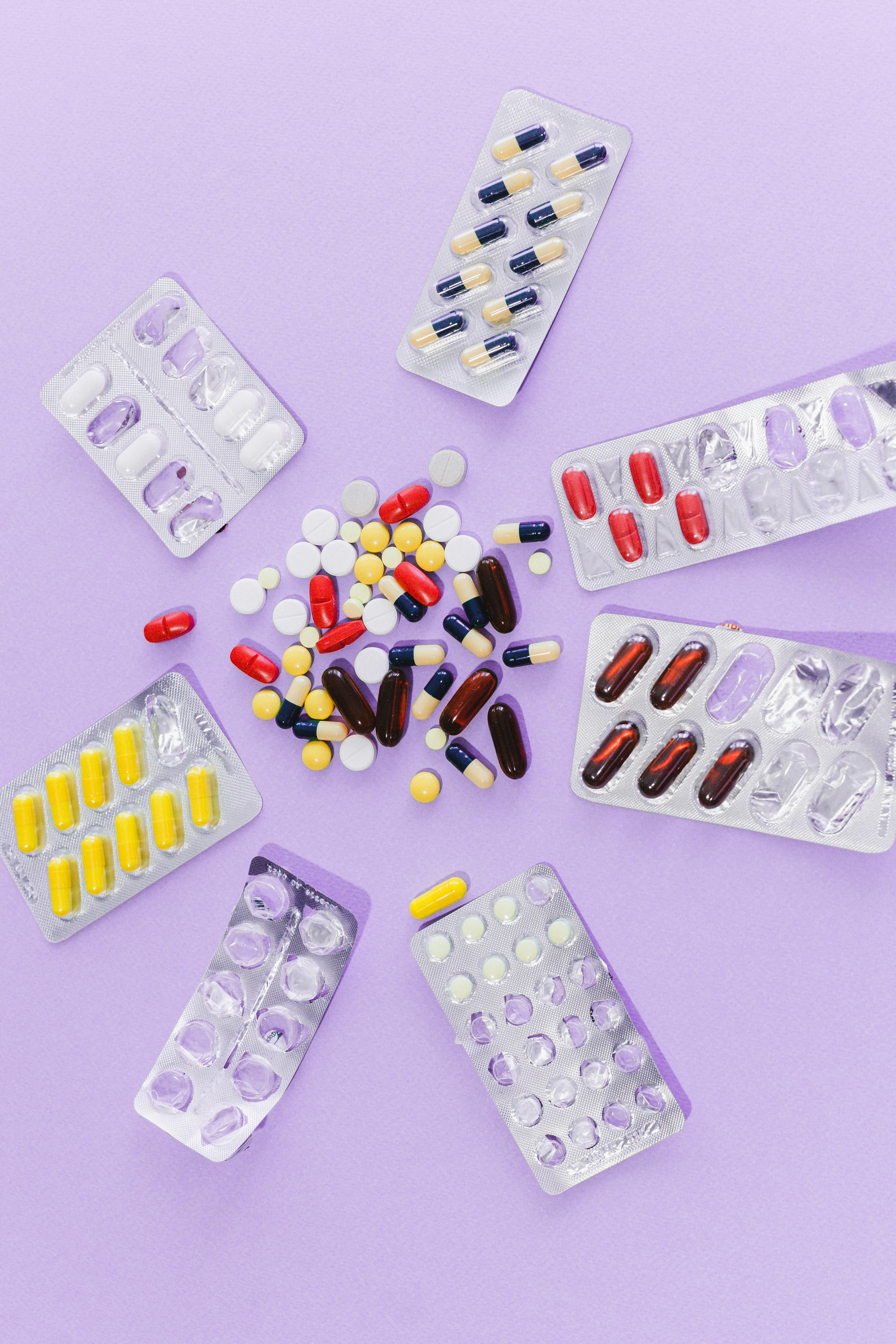 assorted tablets and capsules on purple surface