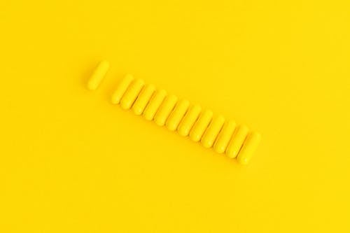 Free Yellow Capsules on Yellow Surface Stock Photo