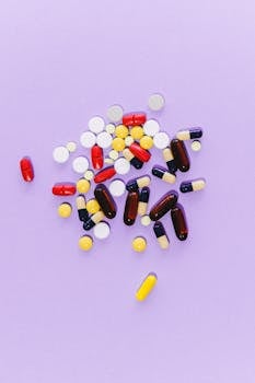 Top view of assorted colorful pills and capsules on a purple surface, ideal for healthcare themes.