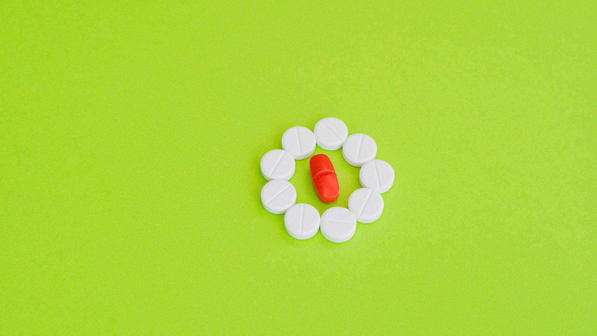 Modafinil Starting Dose: Your Comprehensive Guide White tablets encircle a red pill on a bright green background, symbolizing choice.