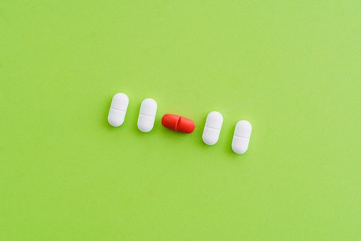 Close-up of colorful pills arranged on a bright green surface representing healthcare.