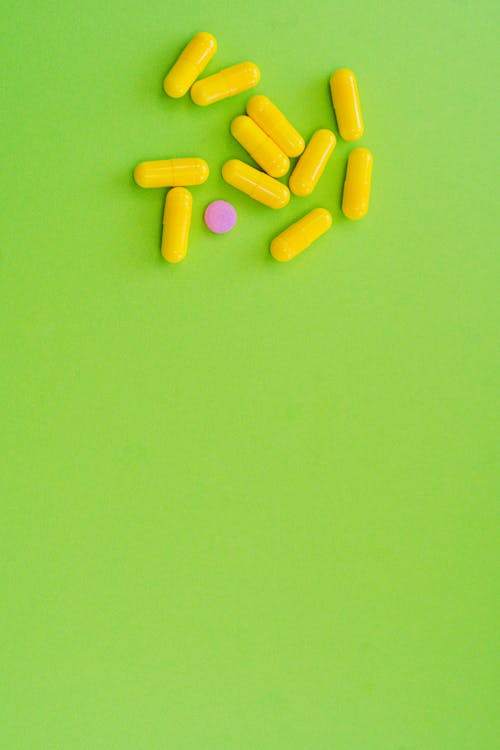 Capsules and Pill on Green Surface