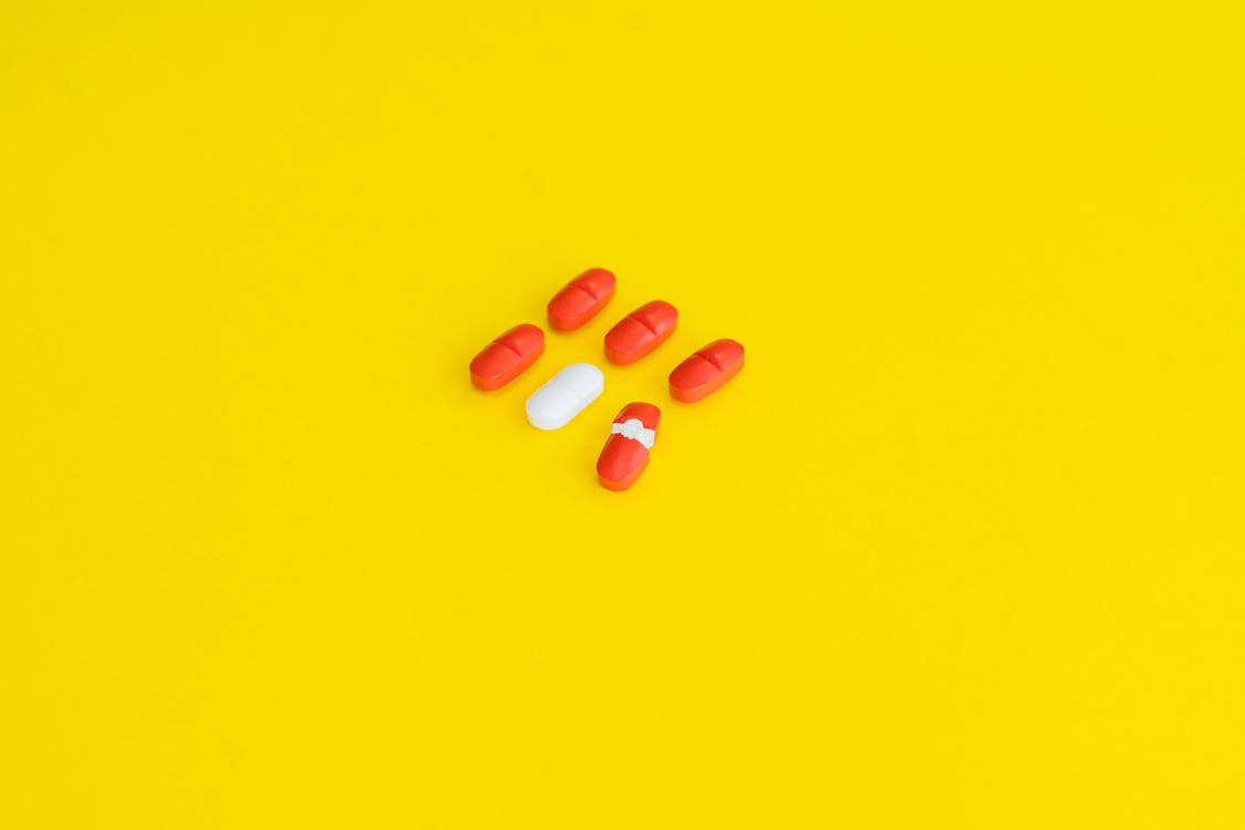 Orange Medication Pill on Yellow Surface