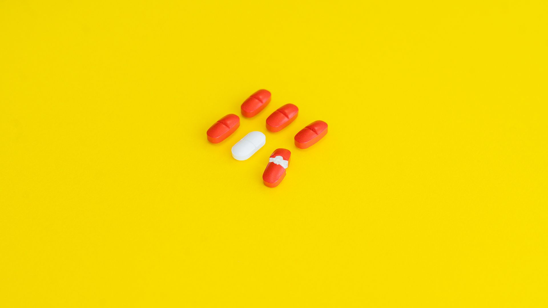 Adrafinil vs Modafinil: Unlocking the Differences Close-up of red and white capsules arranged on a vivid yellow surface — adrafinil vs modafinil
