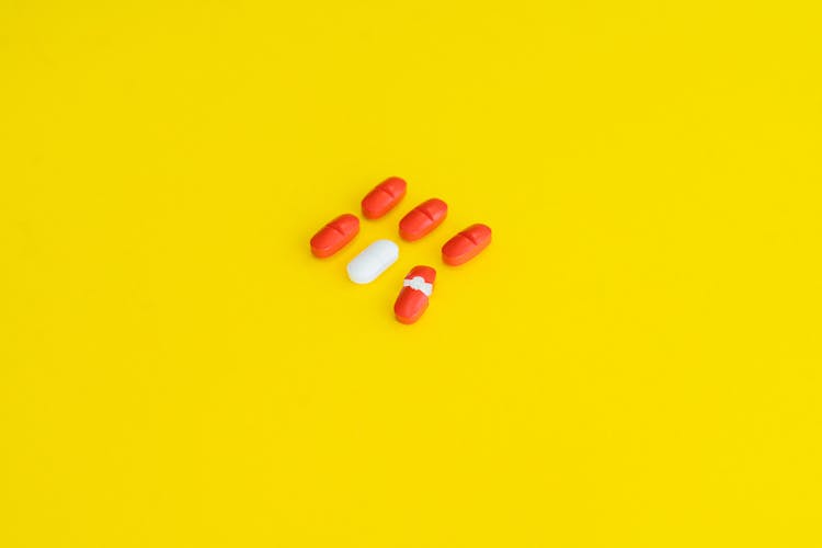 Orange Medication Pill On Yellow Surface