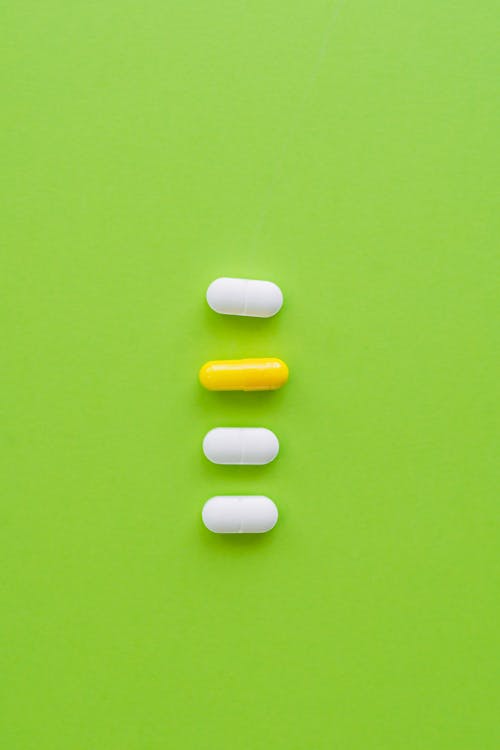 Pills and a Capsule on a Green Surface